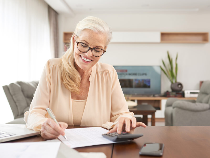 A mature woman is using a calculator.